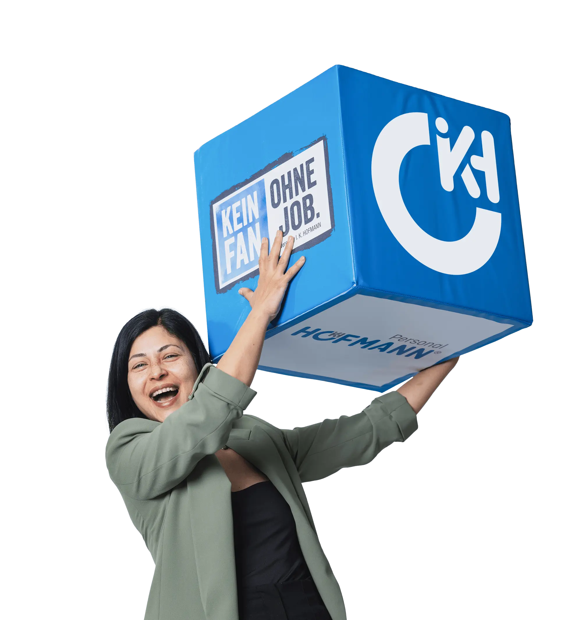 Lachende Mitarbeiterin in einem grünen Blazer hebt einen großen Würfel mit der Bildmarke in die Luft.