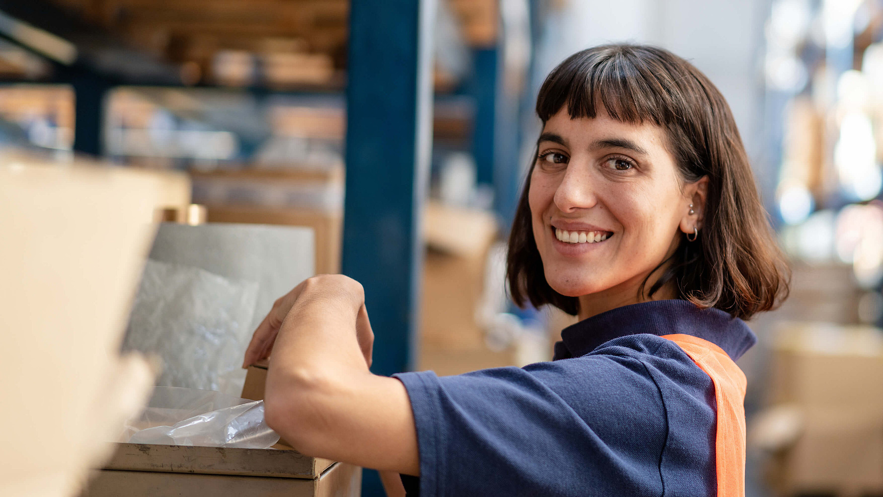 Fachkraft für Lagerlogistik sortiert Waren in einem Regal, mit Fokus auf präzises Arbeiten und Logistikprozesse.