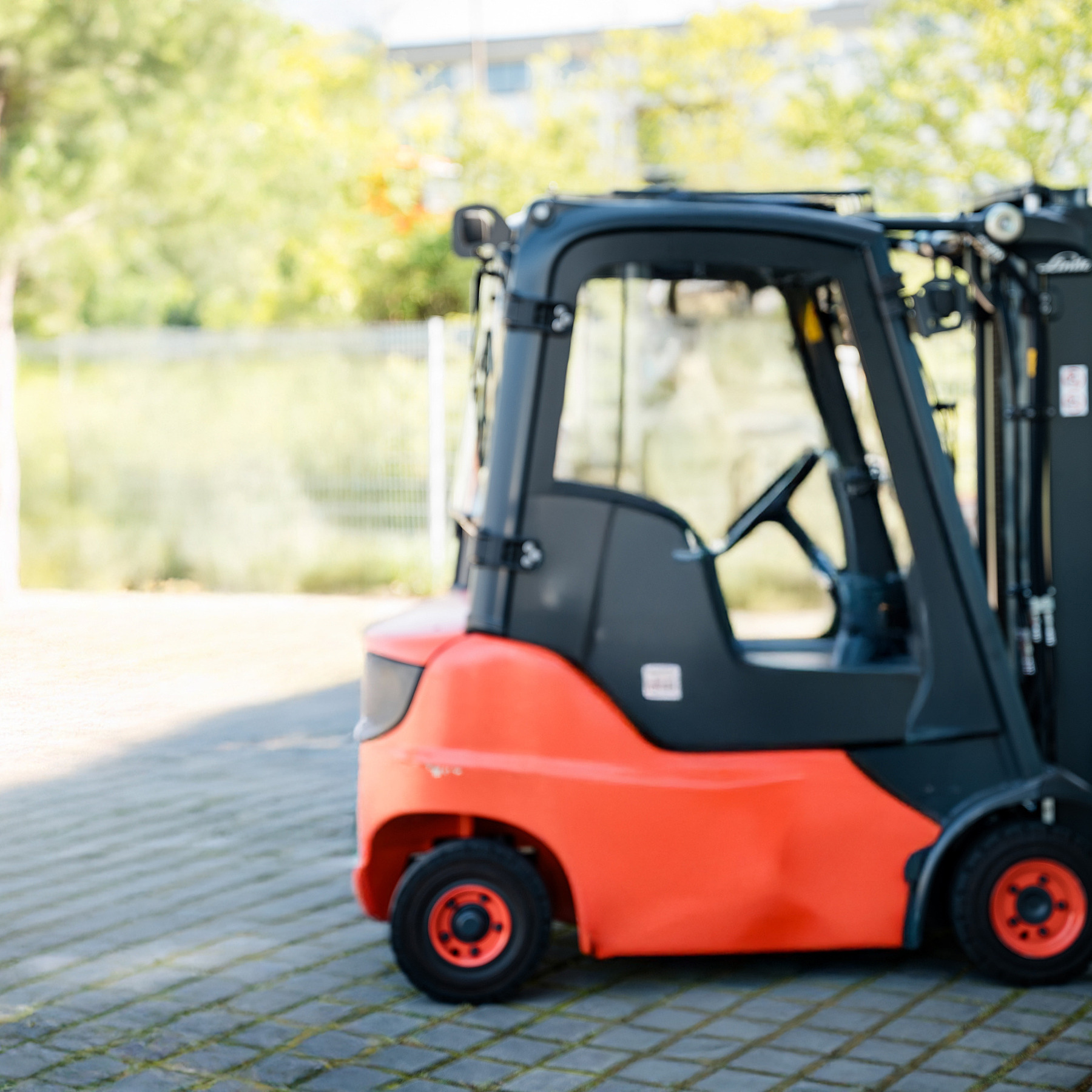 Roter Gabelstapler steht auf einem gepflasterten Außenbereich.