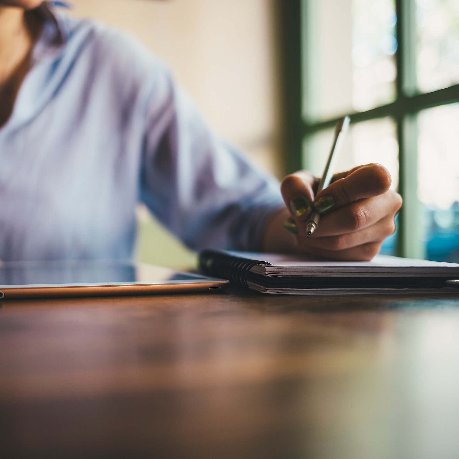 Buchhalter in Businesskleidung arbeitet am Schreibtisch mit Tablet und Notizbuch.