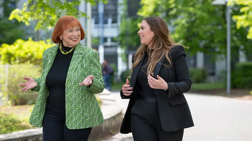Fr. Hofmann und Tochter Sonja gehen im Freien nebeneinander und unterhalten sich freundlich über Hofmann Personal.
