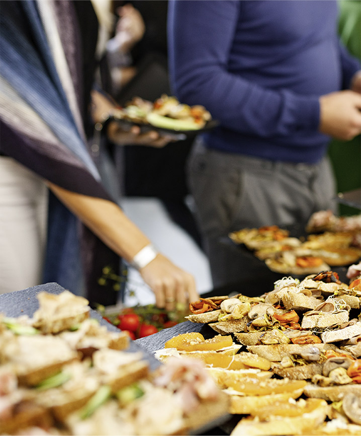 Gäste bedienen sich an einem Buffet mit belegten Häppchen und Fingerfood.